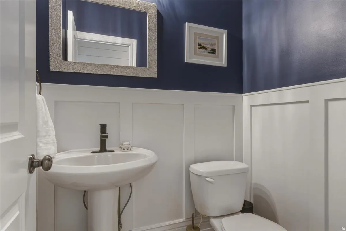 Pedestal sink with dark bronze faucet, framed mirror, and board and batten wainscoting