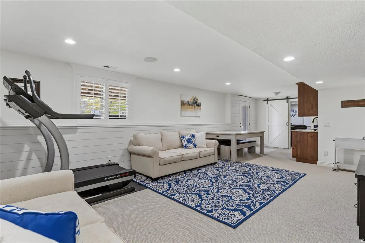 Spacious recreation area featuring recessed lighting, white shiplap wainscoting, and carpet flooring