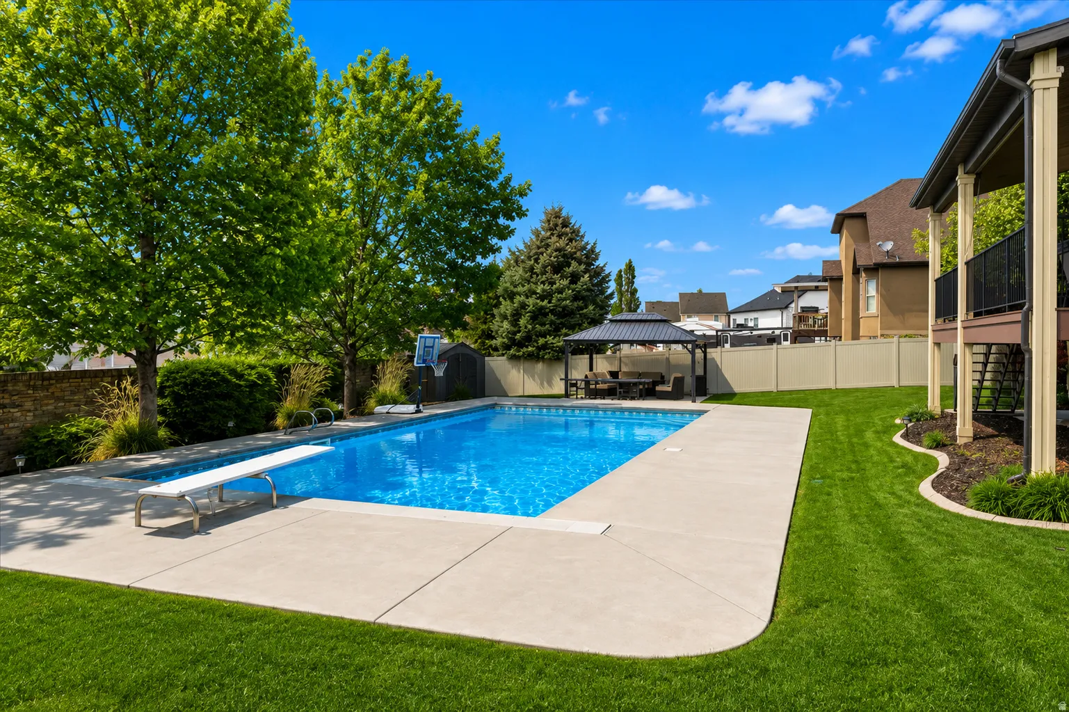 In-ground swimming pool with diving board and expansive concrete surround
