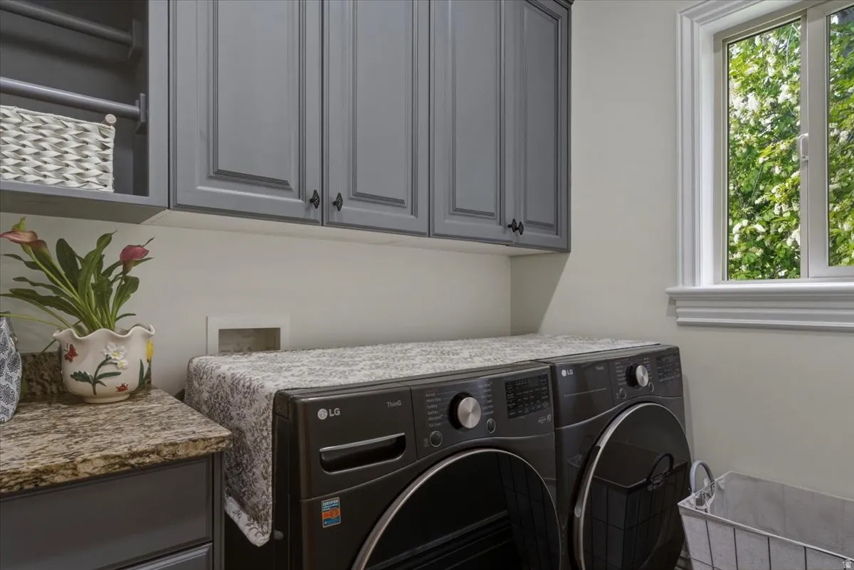 Laundry room featuring gray shaker-style cabinetry, a built-in hanging rod, a granite-look countertop, and a window with white trim