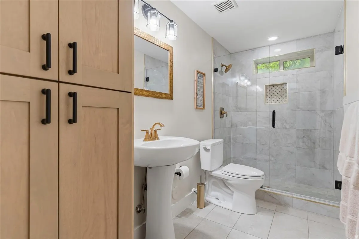 Full bathroom featuring a walk-in shower with marble-style tile surround, integrated niche, and a glass enclosure