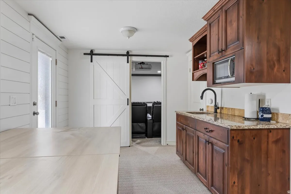 Wet bar-second kitchen potential featuring rich wood cabinetry, granite countertop, and integrated microwave