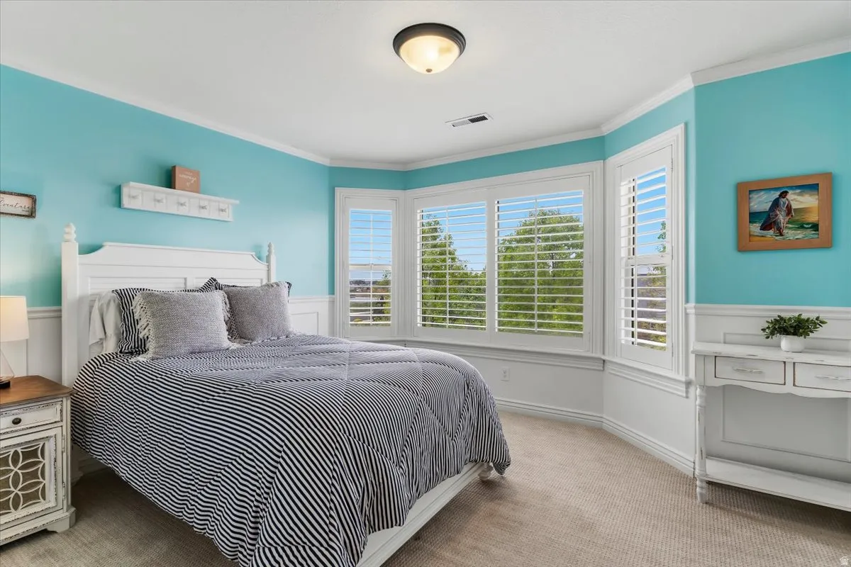 Room featuring a bay window with plantation shutters, crown molding, two-tone wall treatment with wainscoting, and a semi-flush mount ceiling light
