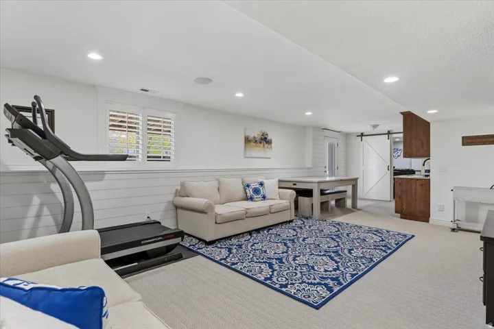 Spacious recreation area featuring recessed lighting, white shiplap wainscoting, and carpet flooring