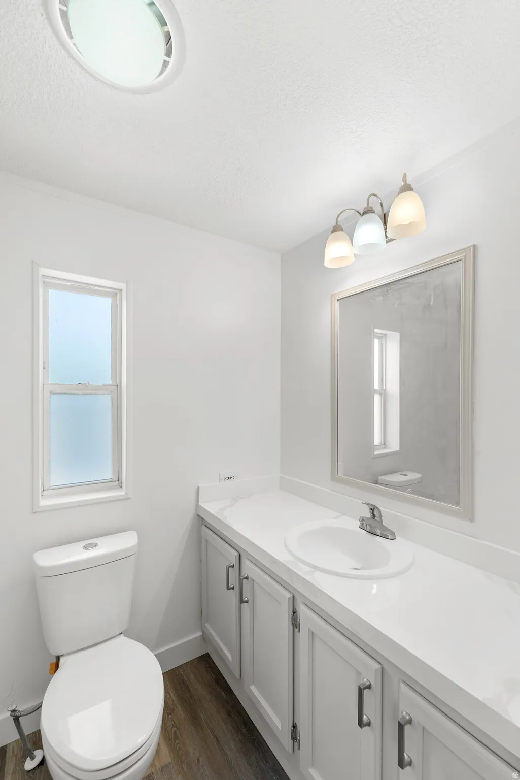 Bathroom featuring a single vanity with a white countertop, undermount sink, and brushed nickel faucet