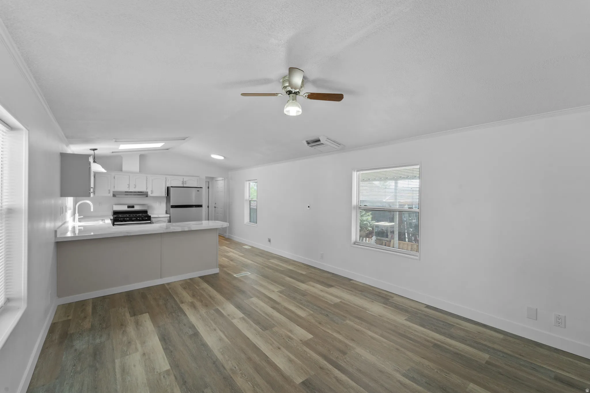 Open-concept living area featuring wood-finish flooring, vaulted ceilings, and a ceiling fan