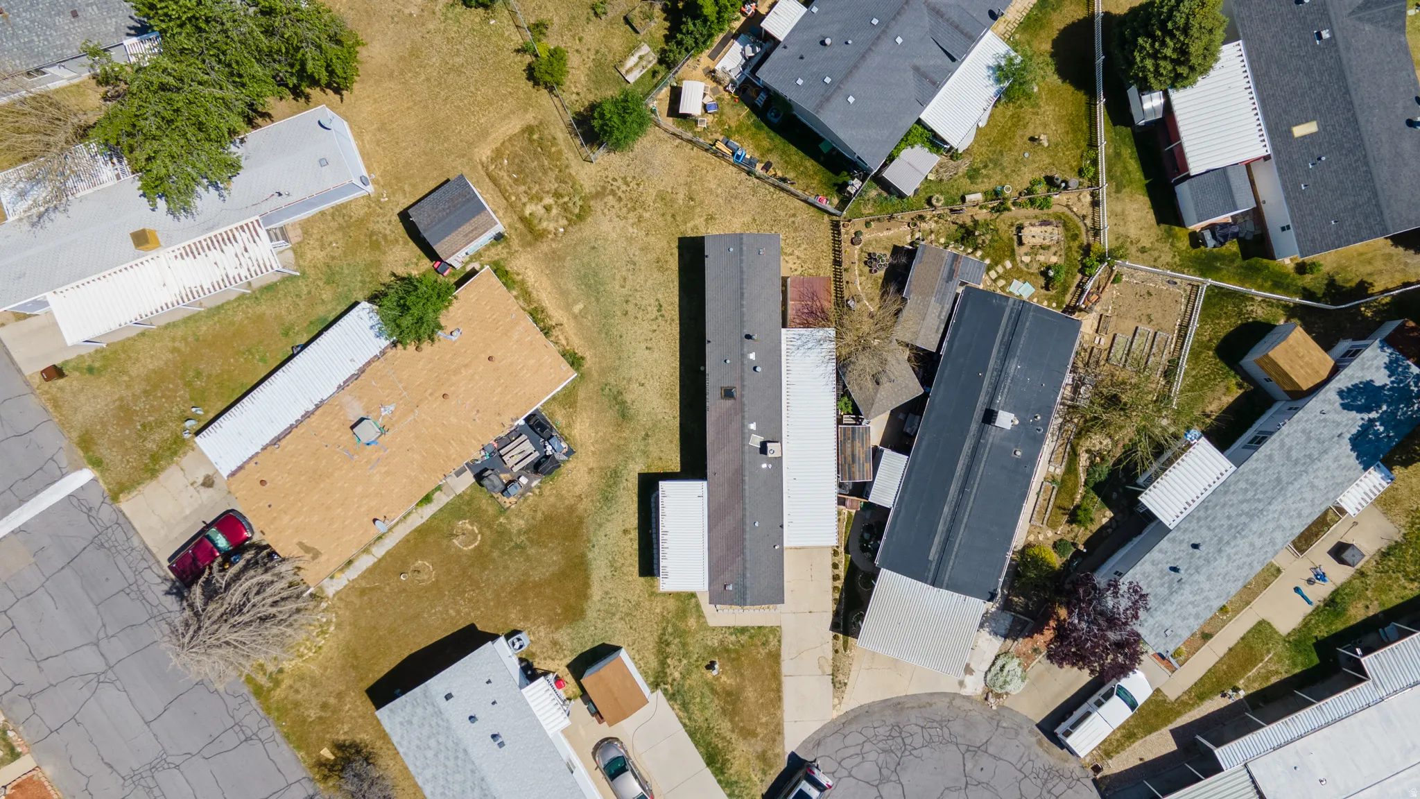 Aerial view of the property and surrounding neighborhood, featuring multiple residential structures with various roofing materials including dark shingle, light shingle, and flat membrane roofs