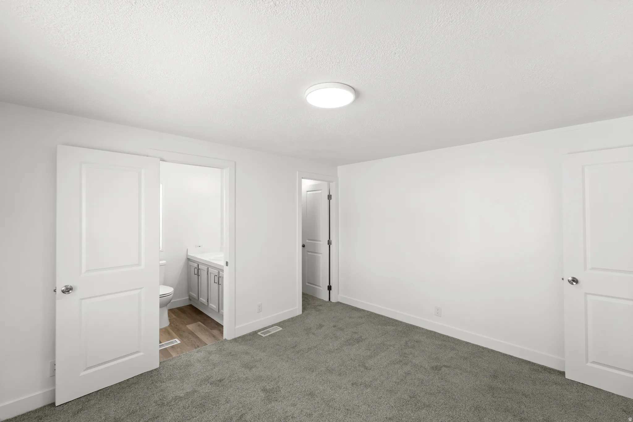 Spacious room featuring neutral carpeting, a modern flush-mount ceiling light, and white walls