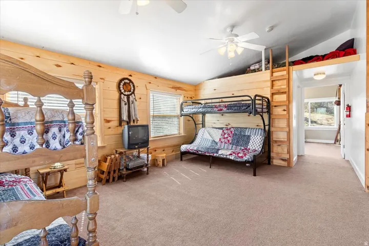 Room featuring light wood paneling, a vaulted ceiling, and carpet flooring