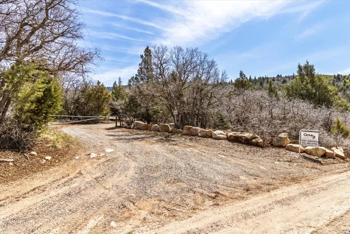 Gravel road entry point framed by natural rock landscaping and a wooded hillside