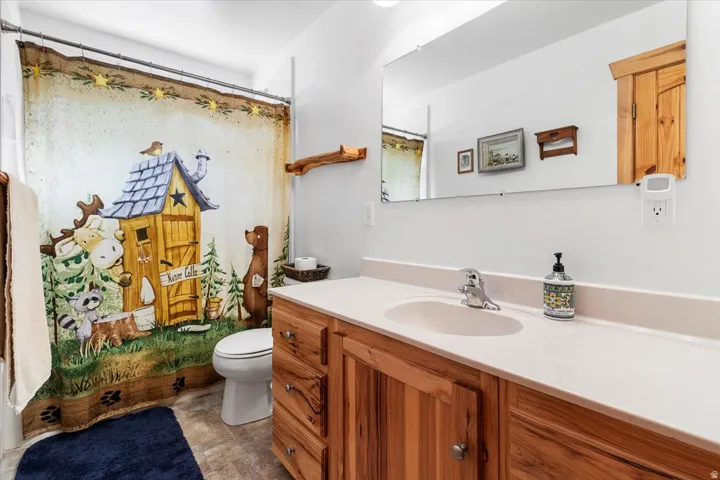 Bathroom featuring a vanity with wood-finish cabinetry, a single basin sink, and a large wall-mounted mirror