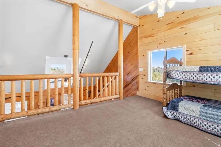 Loft area featuring natural wood paneling and a log railing