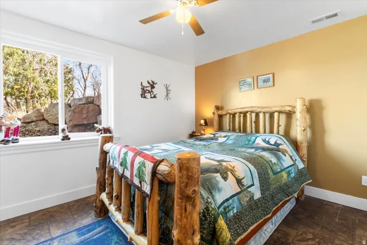 Room featuring a ceiling fan, a window with exterior rock landscaping, and tile flooring