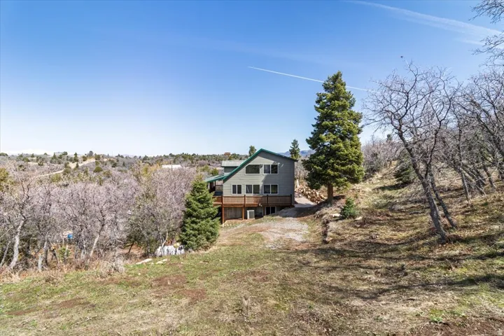 Residence featuring a multi-level design with a green roof, light gray siding, and a wooden deck
