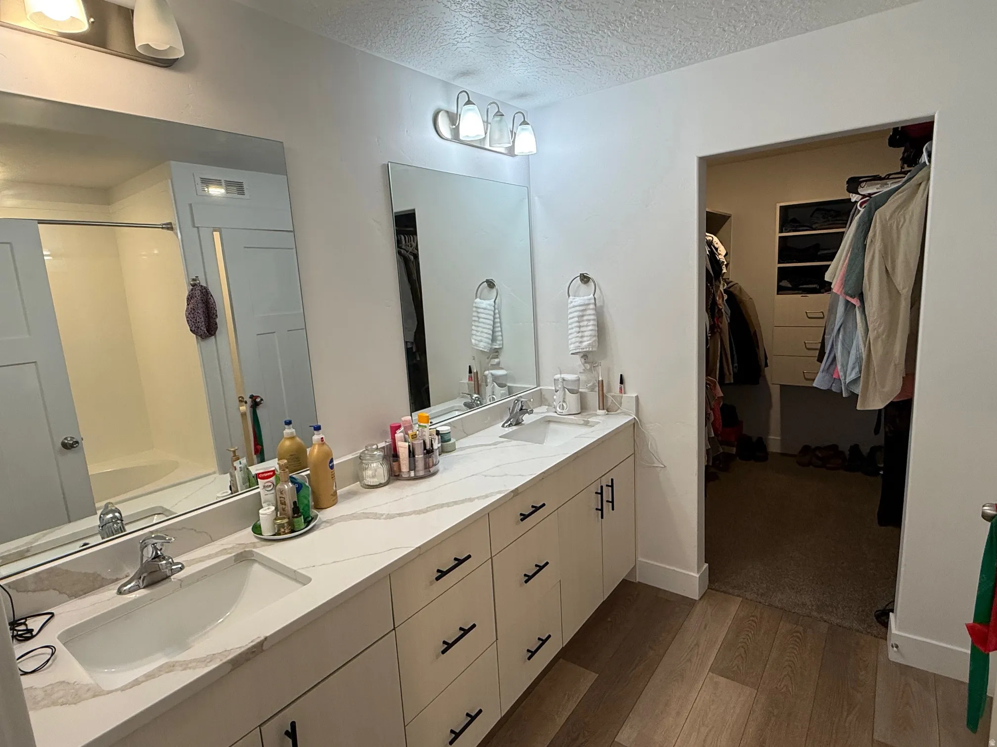 Dual vanity with white cabinetry and dark hardware, featuring white countertops and undermount sinks