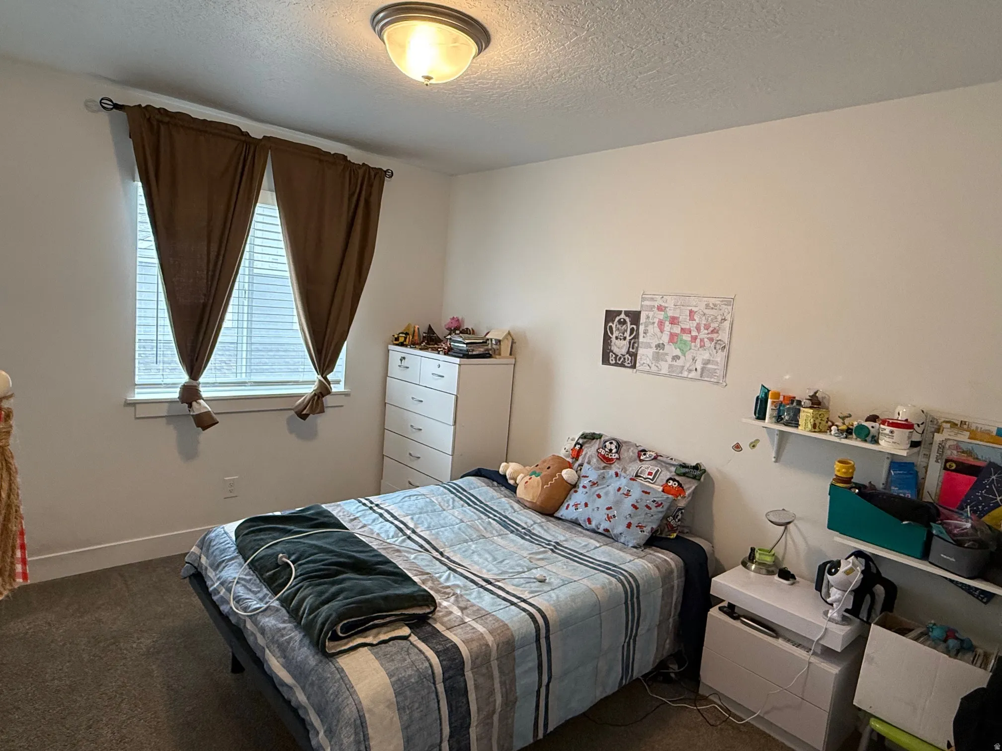 Carpeted room featuring a ceiling-mounted light fixture, white walls, and a window with blinds