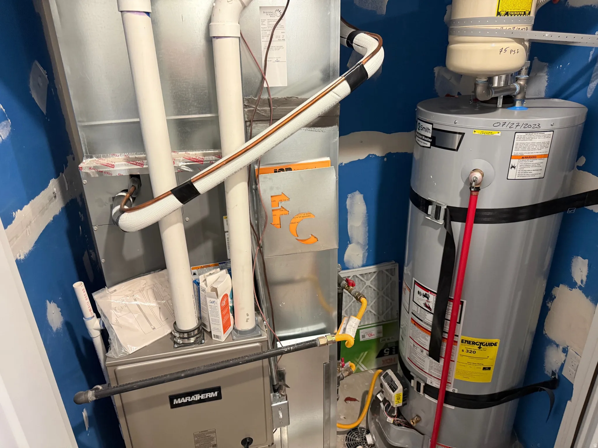 Utility closet featuring a water heater, furnace, and exposed ductwork