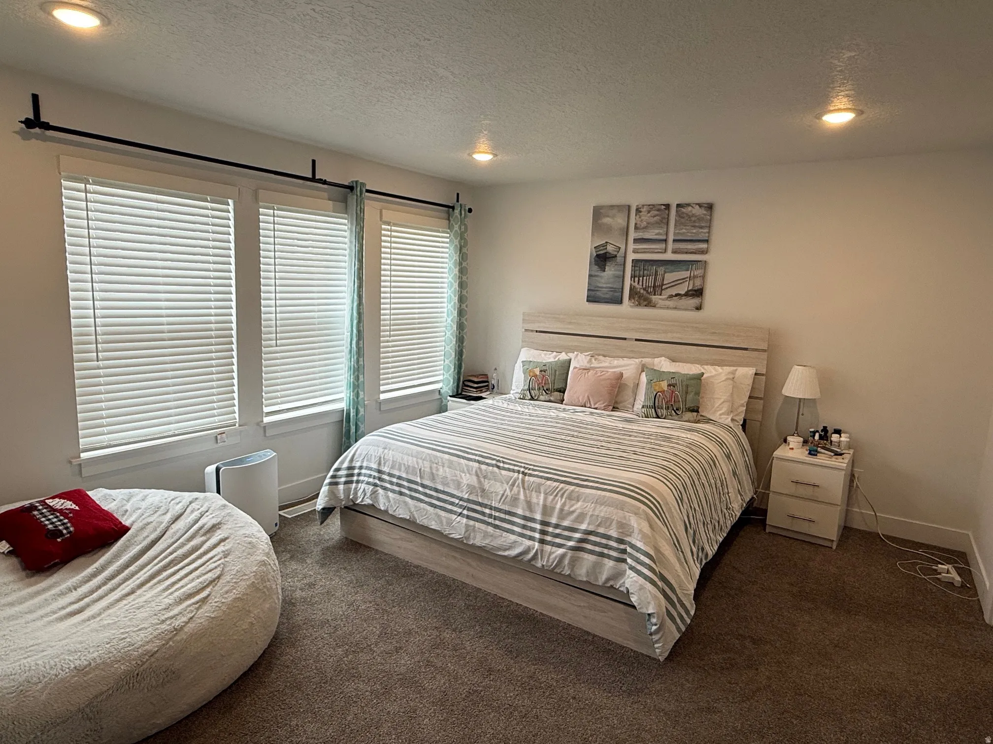 Carpeted room featuring three windows with blinds, recessed lighting, and a light-toned wood-finish headboard