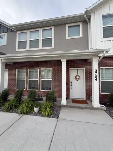 Contemporary townhome exterior featuring a brick facade on the lower level and stucco on the upper level