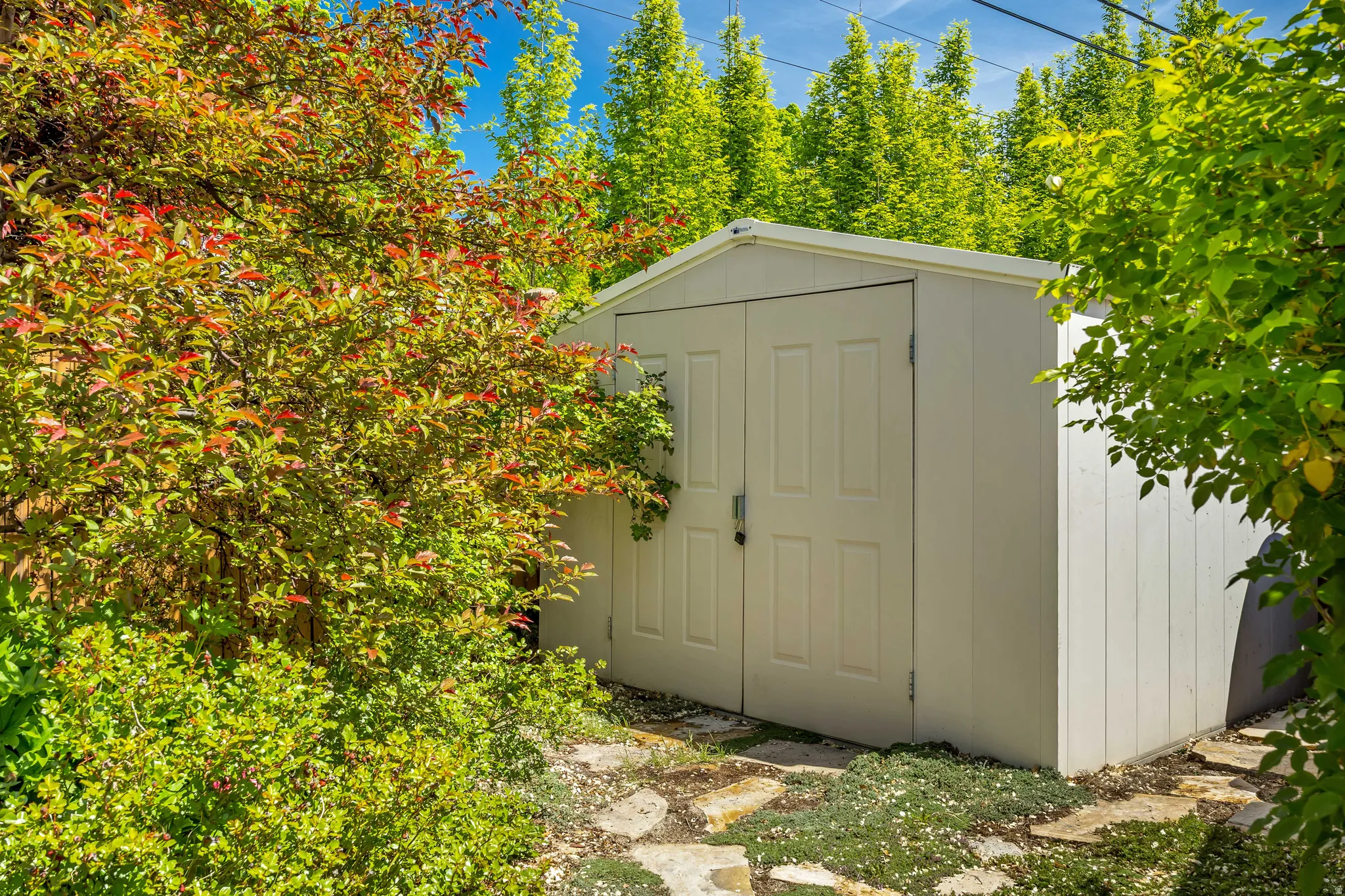 White storage shed featuring paneled double doors and vertical siding