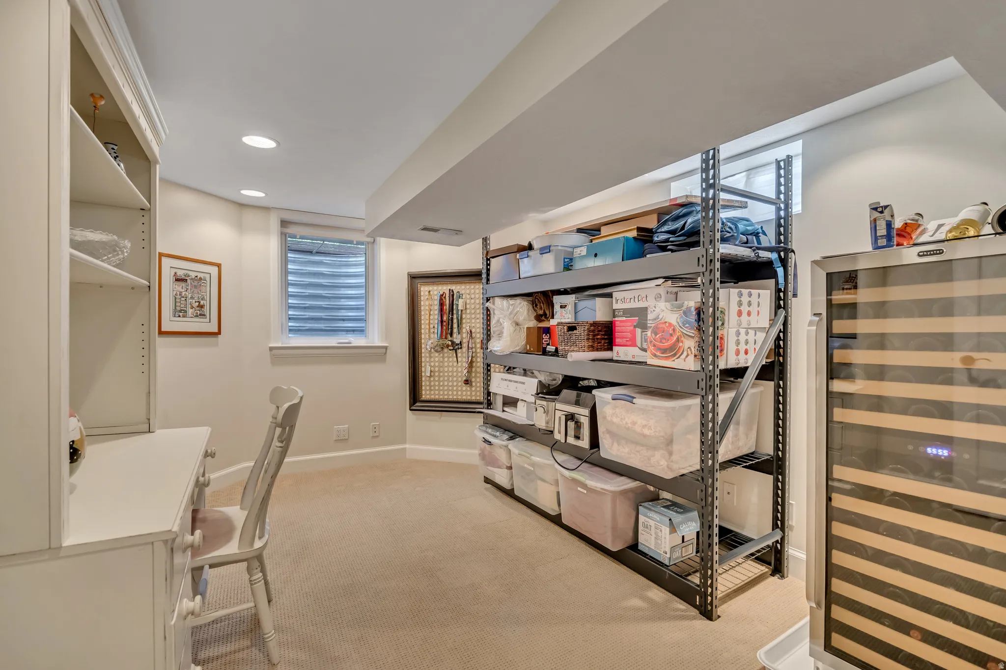 Carpeted lower level room featuring recessed lighting, built-in shelving, a dual-zone beverage cooler, and two windows with blinds
