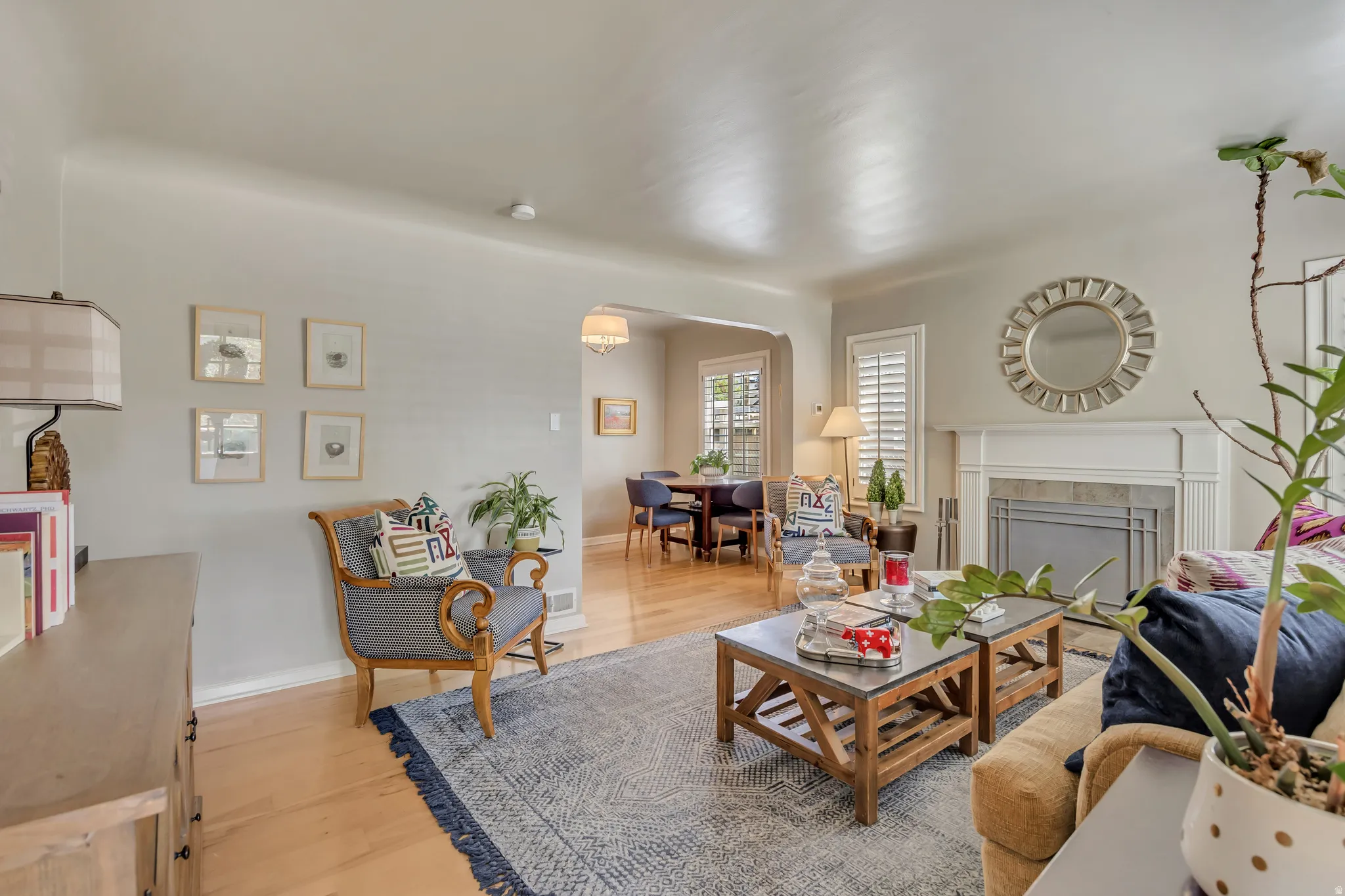 Living area featuring wood-finish flooring, a fireplace with a mantel and tile surround, and an arched entry to the dining area
