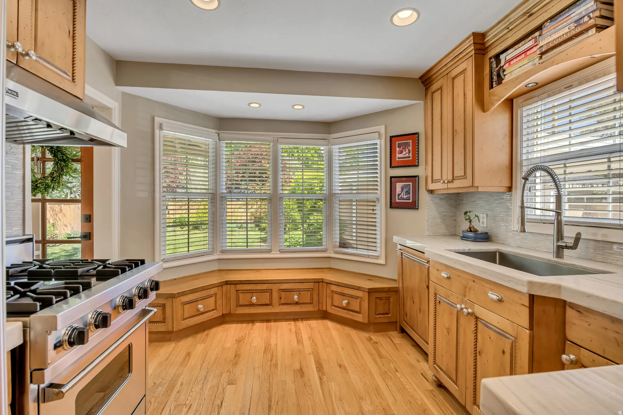 Kitchen featuring wood-finish flooring, custom wood cabinetry, and a built-in window bench with storage