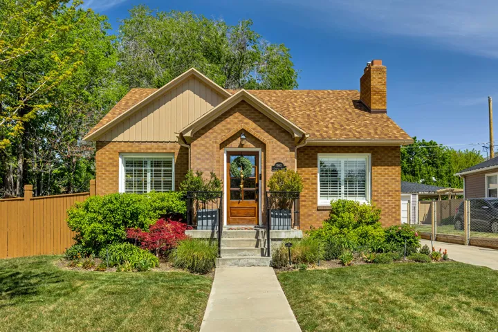 Brick facade residence featuring a front gabled entry, a prominent brick chimney, and a brown shingle roof