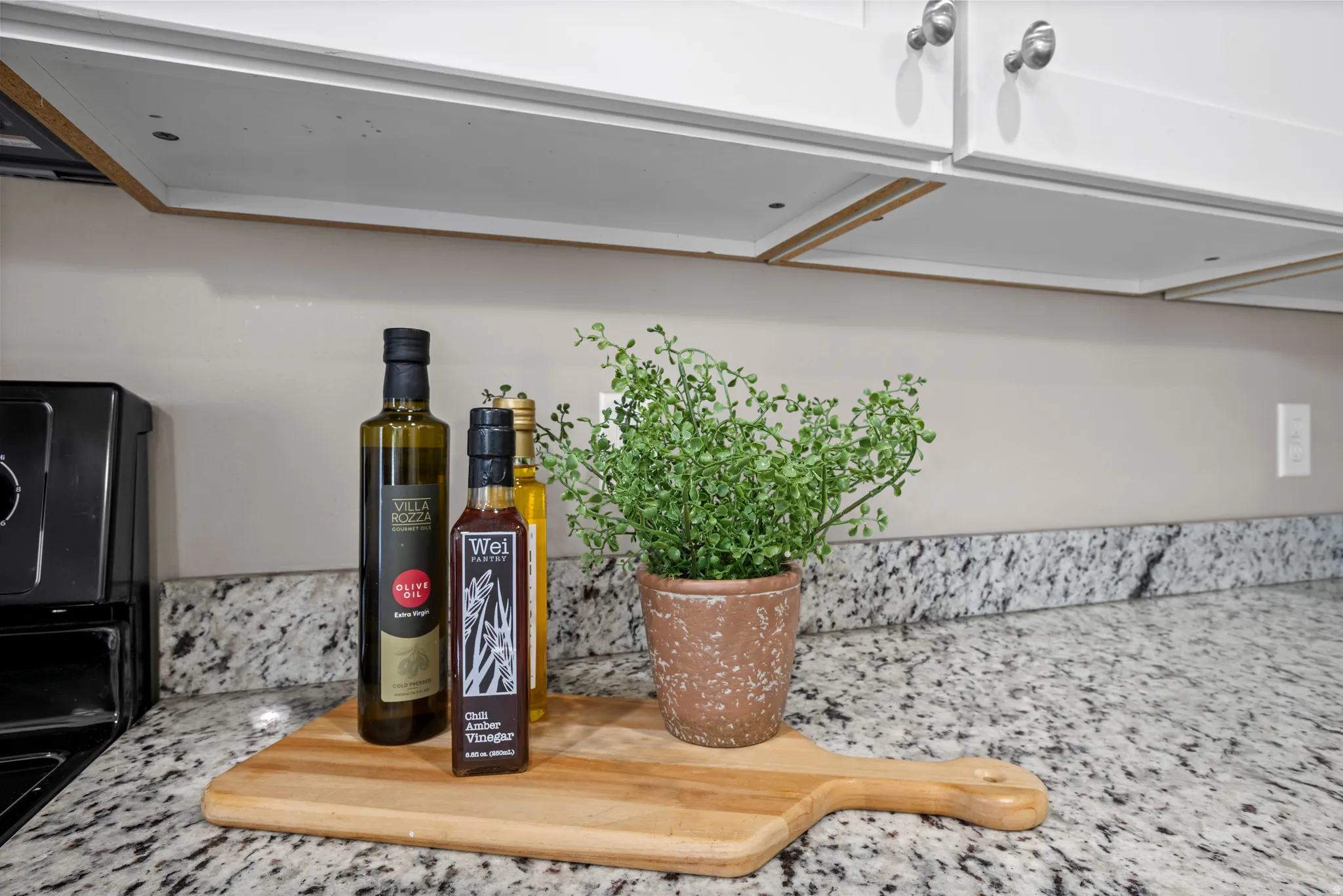 Granite-style countertops featuring a matching backsplash and white upper cabinetry with brushed nickel hardware