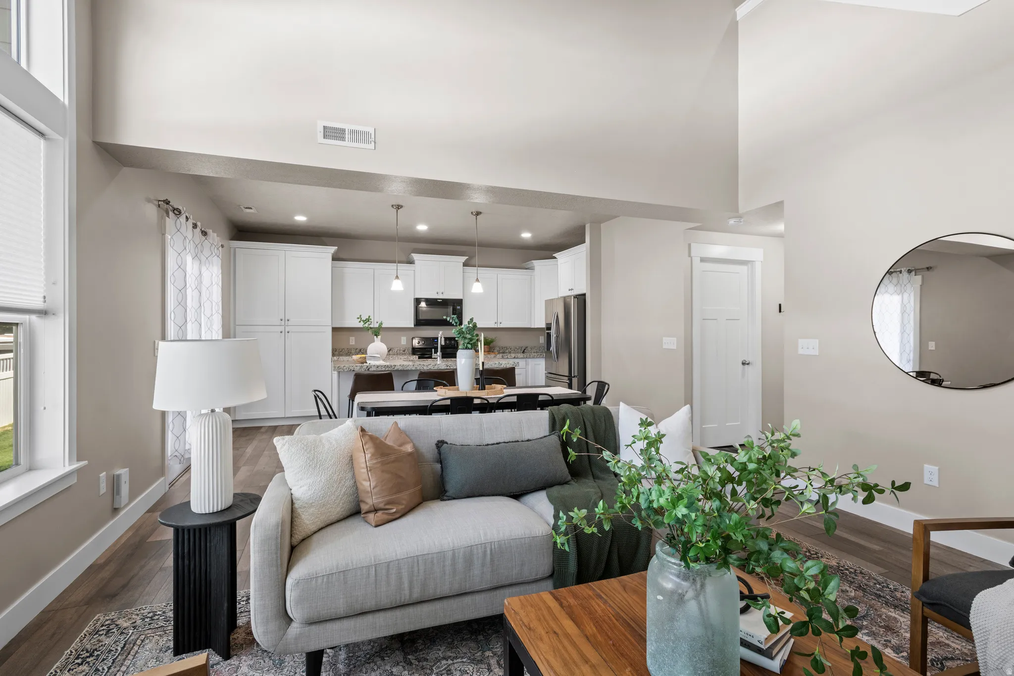 Expansive open-concept living space featuring vaulted ceilings, wood-finish flooring, and light neutral wall tones