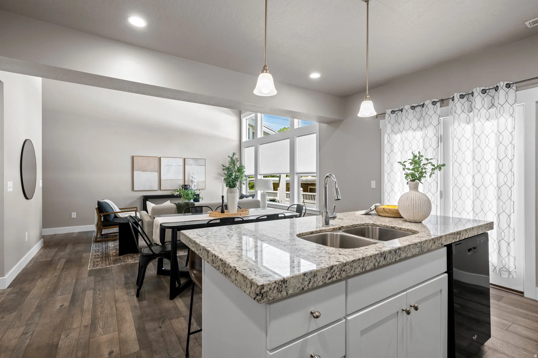 Kitchen island featuring a dual-basin stainless steel sink, gooseneck faucet, and light-toned granite countertop