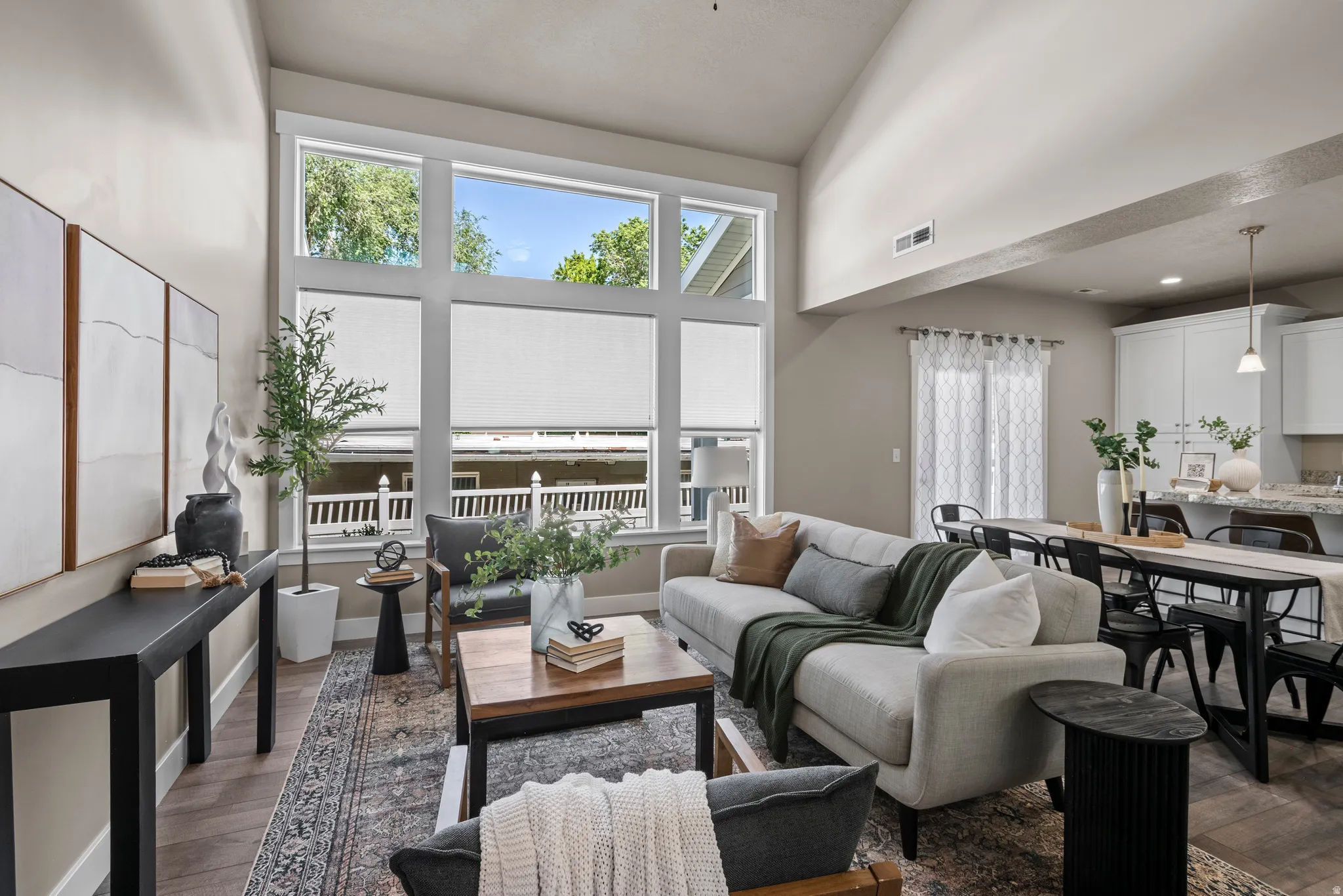 Spacious living area featuring high ceilings and large windows with integrated blinds