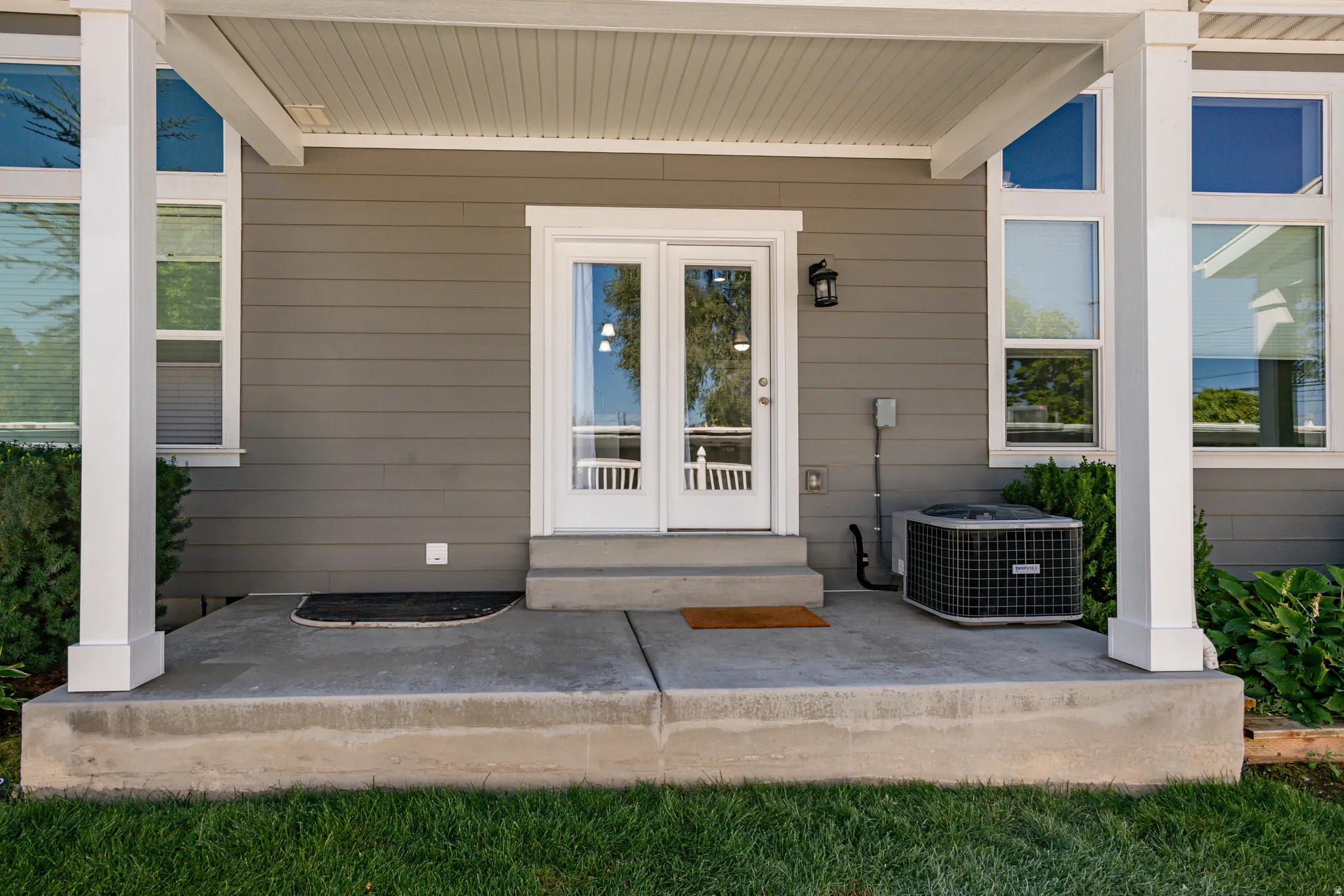 Patio area featuring concrete flooring, gray siding, white trim, and a double glass-panel door