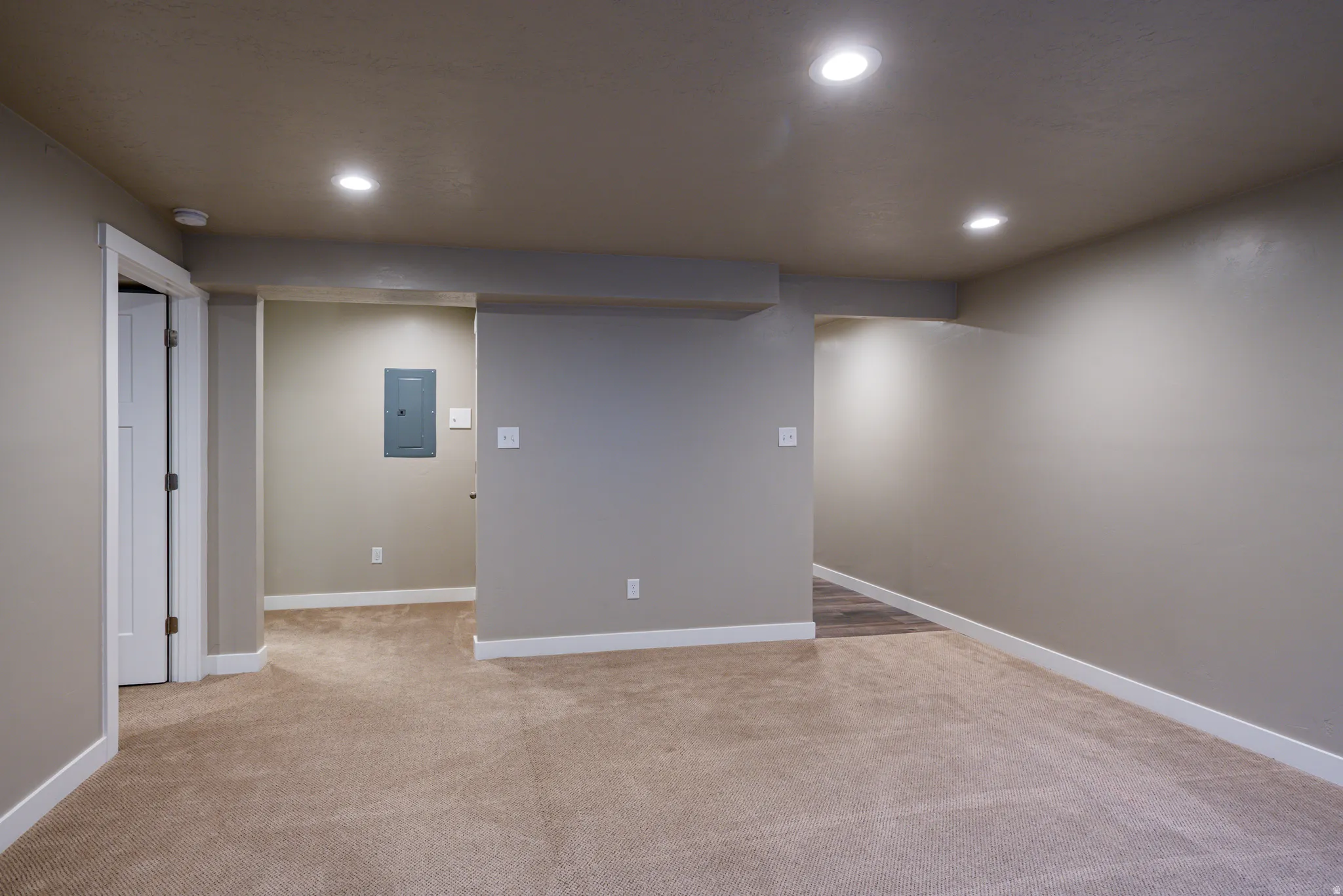 Spacious room featuring neutral carpeting, recessed lighting, and white baseboards