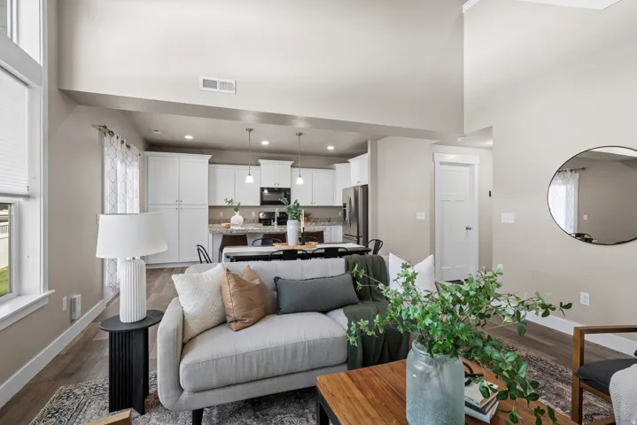 Expansive open-concept living space featuring vaulted ceilings, wood-finish flooring, and light neutral wall tones
