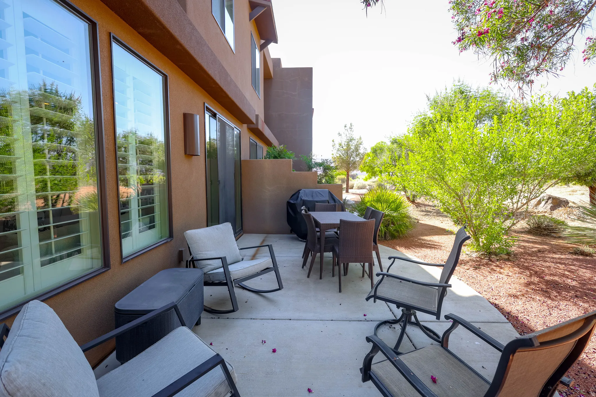 Private concrete patio featuring a desert-adapted landscape with mature trees and shrubs