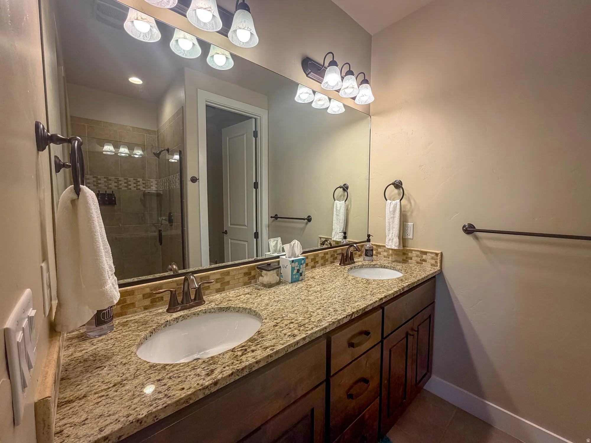 Double vanity with granite countertops, undermount sinks, and dark wood cabinetry