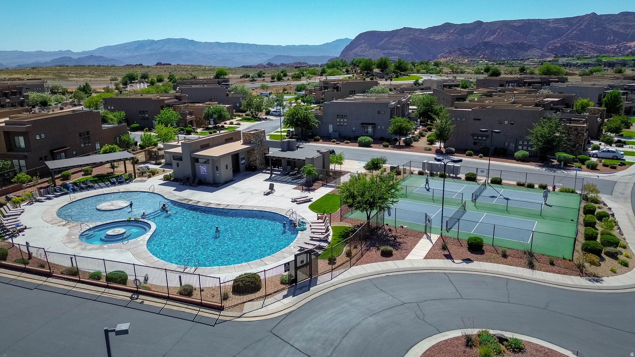 Resort-style amenities featuring a large swimming pool with integrated spa, a dedicated lounging area with chaise lounges and pergolas, and two pickle ball courts