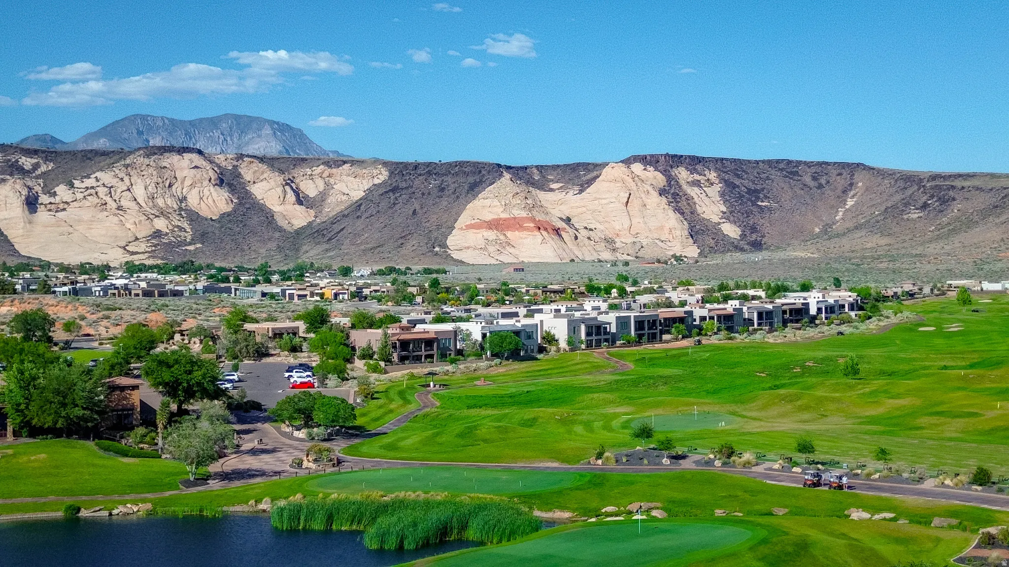 Lush green golf course with putting greens, water features, and expansive mountain backdrops with Fish Rock