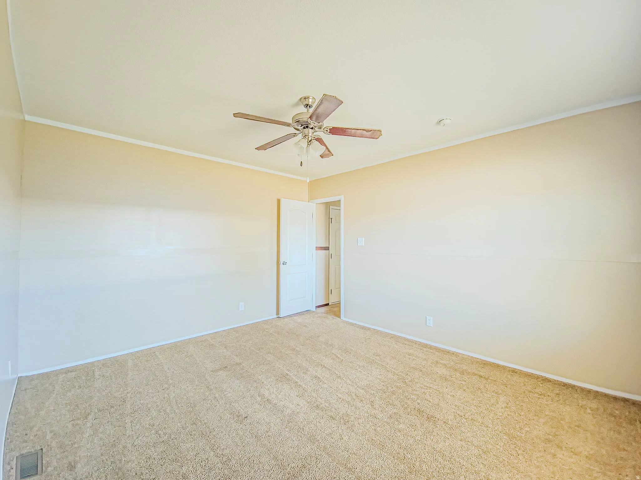 Spacious room featuring neutral carpeting, light-toned walls, and a ceiling fan with integrated lighting