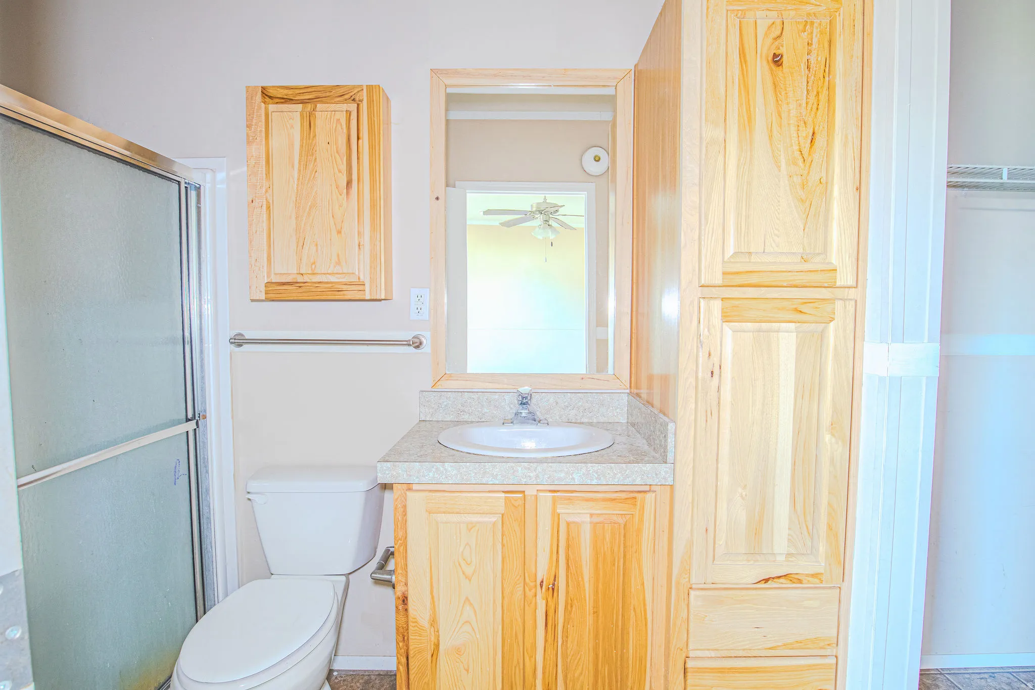 Bathroom vanity with a white basin sink, polished chrome faucet, and a light-toned countertop