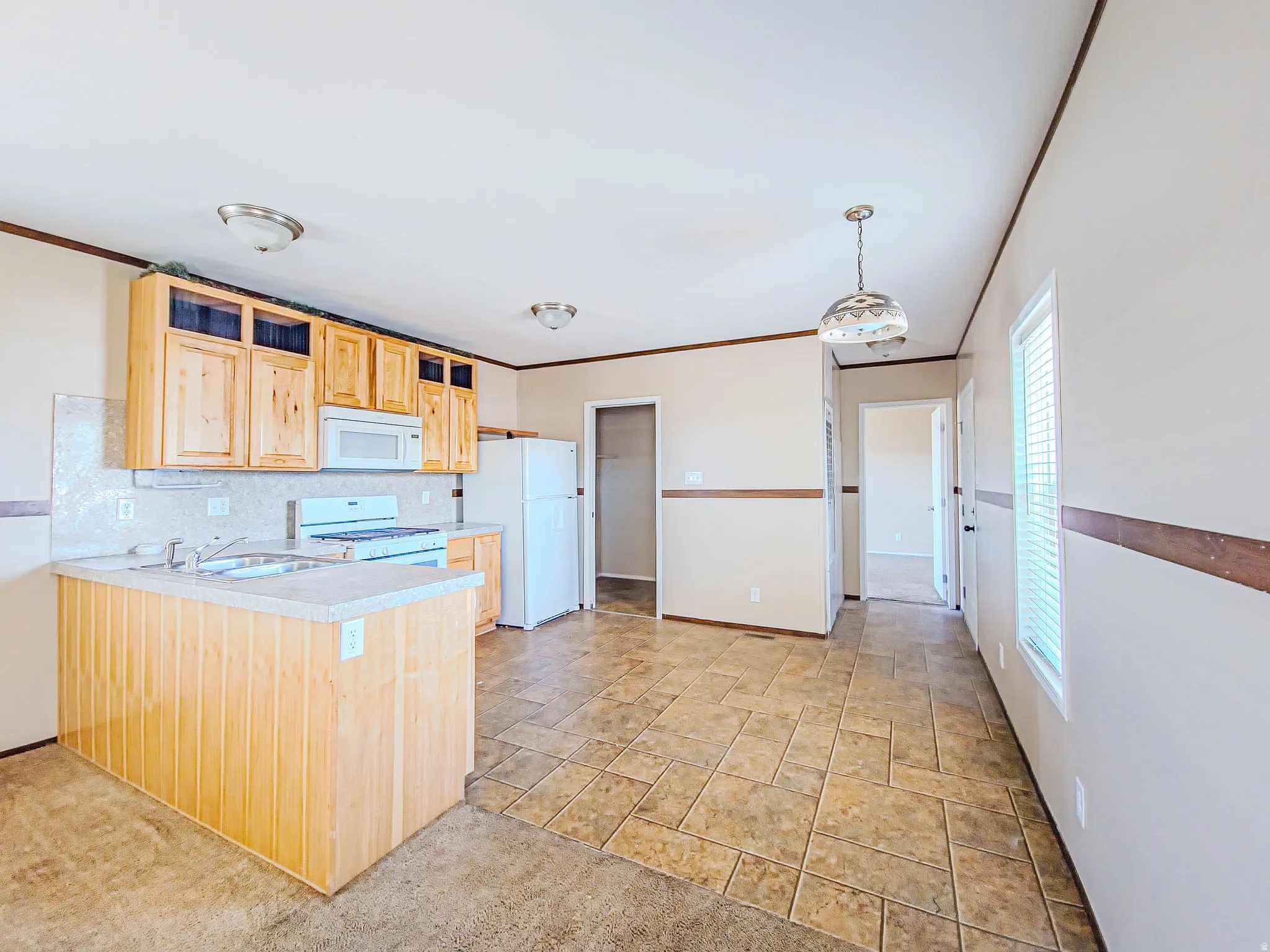 Kitchen space featuring wood cabinetry, white appliances, light-toned countertops, and a tile backsplash