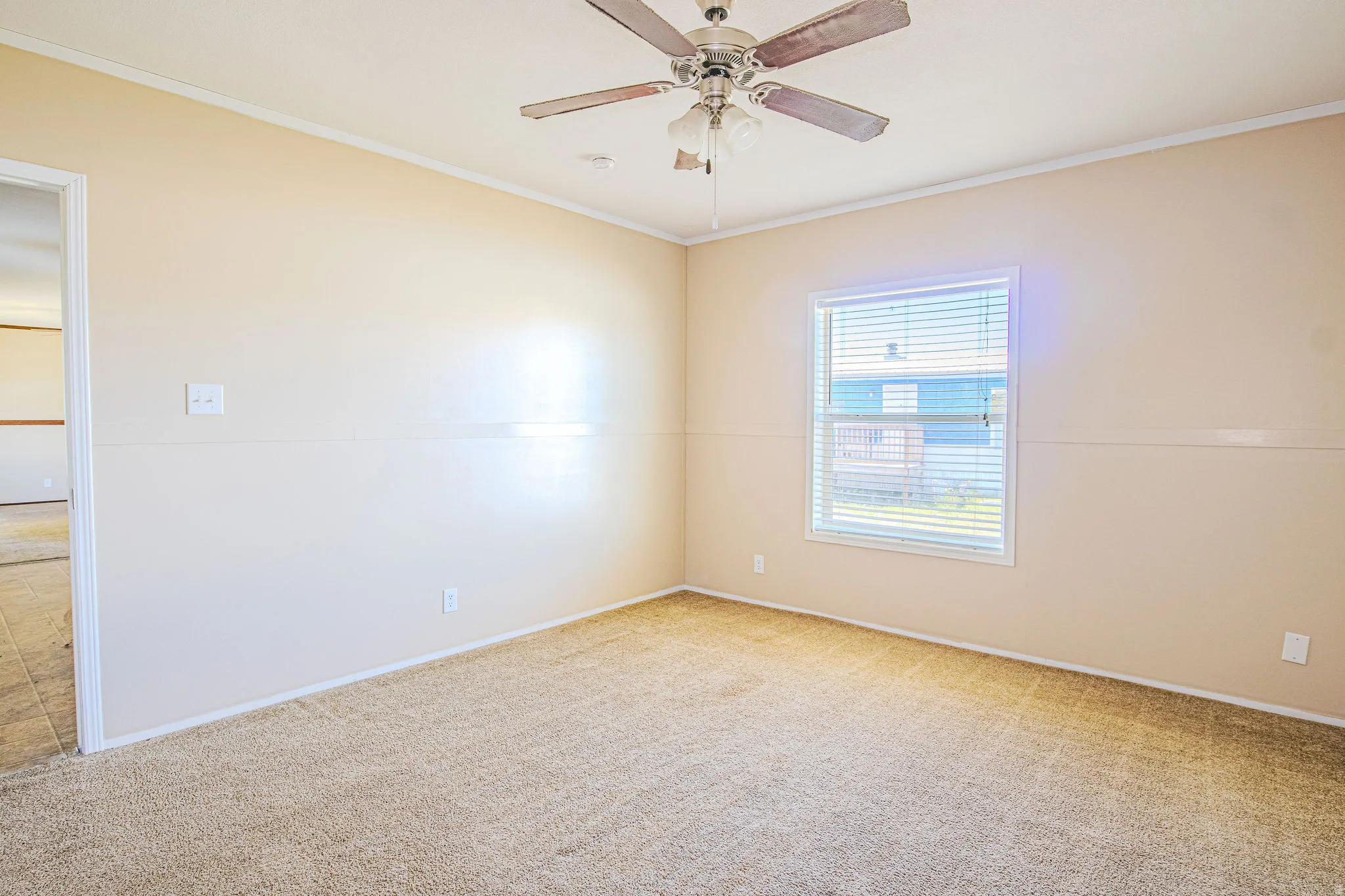 Carpeted room with a ceiling fan, a window featuring horizontal blinds, and neutral-toned walls