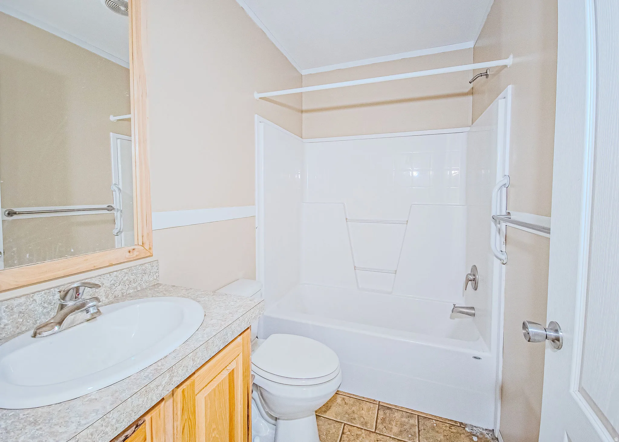 Full bathroom featuring a white tub/shower combination, a toilet, and a vanity with a light-toned countertop and wood-finish cabinetry