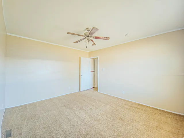 Spacious room featuring neutral carpeting, light-toned walls, and a ceiling fan with integrated lighting