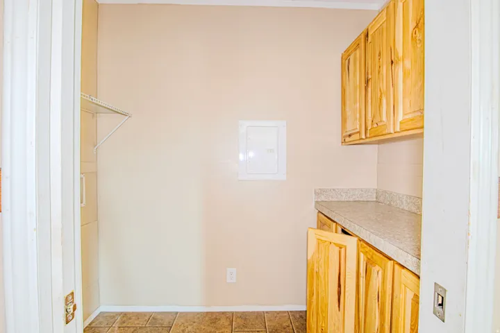 Utility area featuring natural wood cabinetry, a light-toned countertop, and tiled flooring