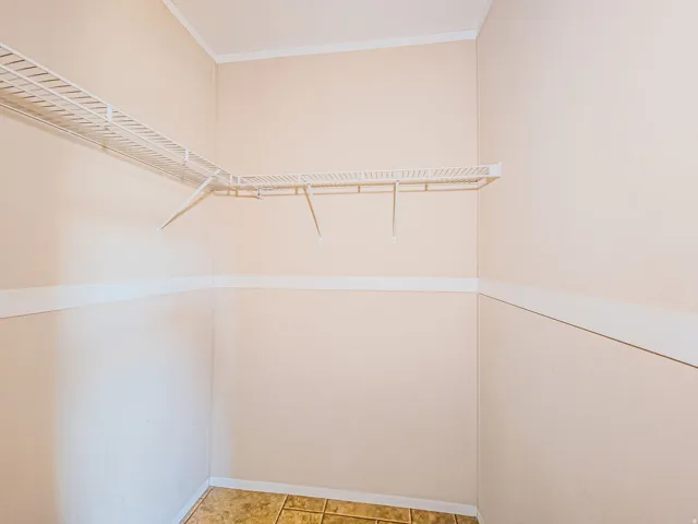 Storage area featuring wire shelving, neutral wall tones, white trim, and patterned floor tiling