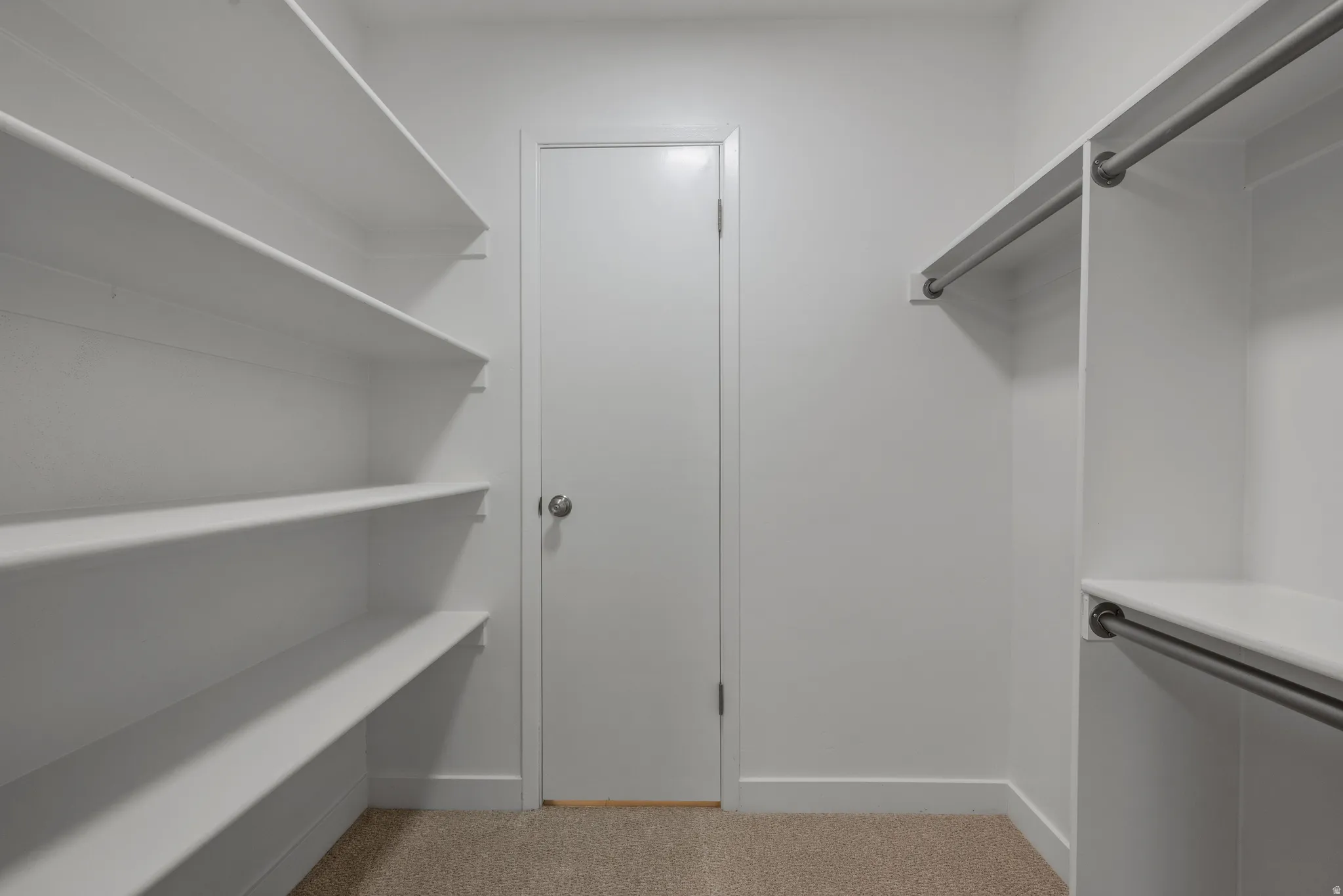 Spacious closet featuring extensive built-in shelving, dual hanging rods, and neutral-toned carpeting