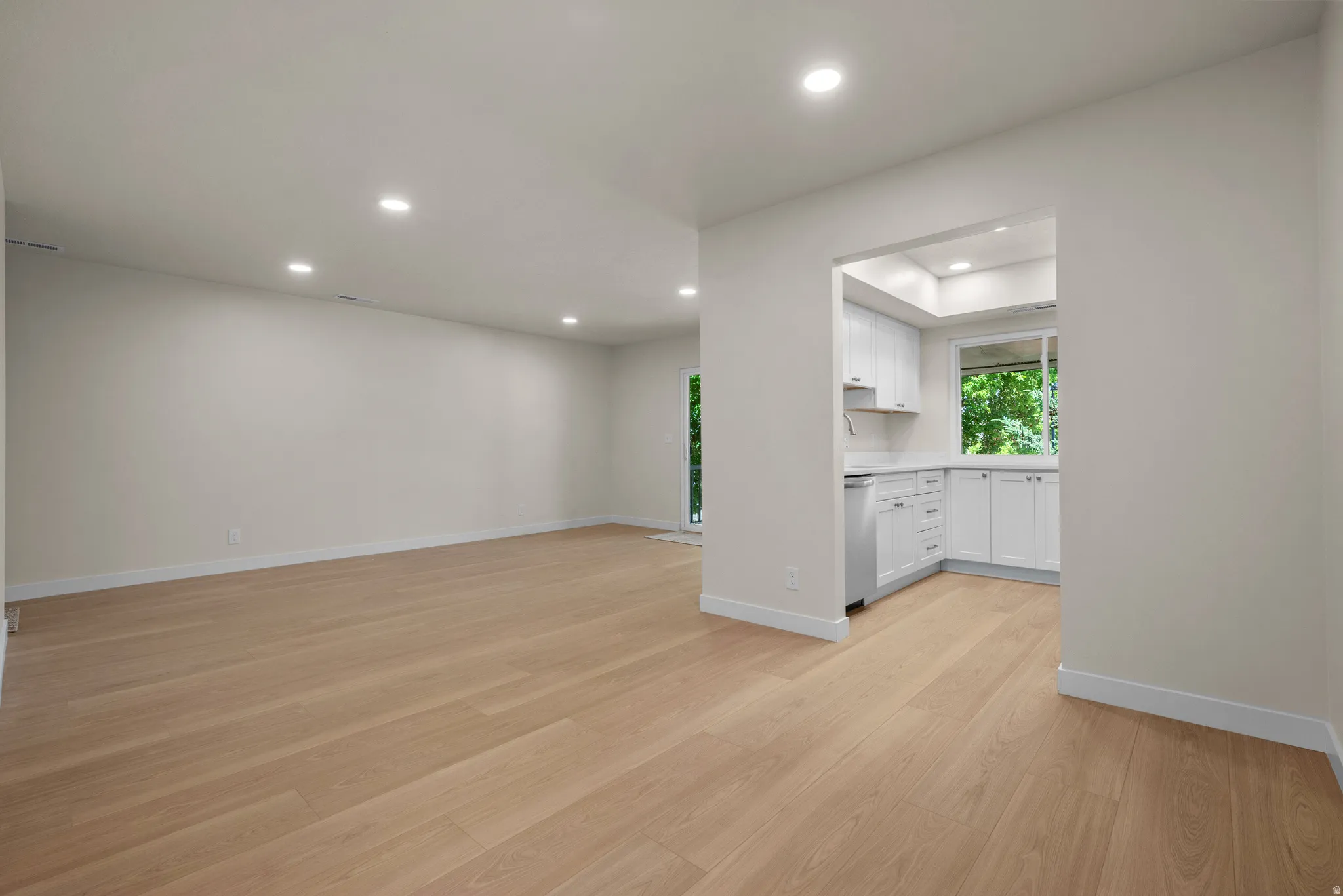 Expansive living area featuring light wood-finish flooring, recessed lighting, and a neutral color palette