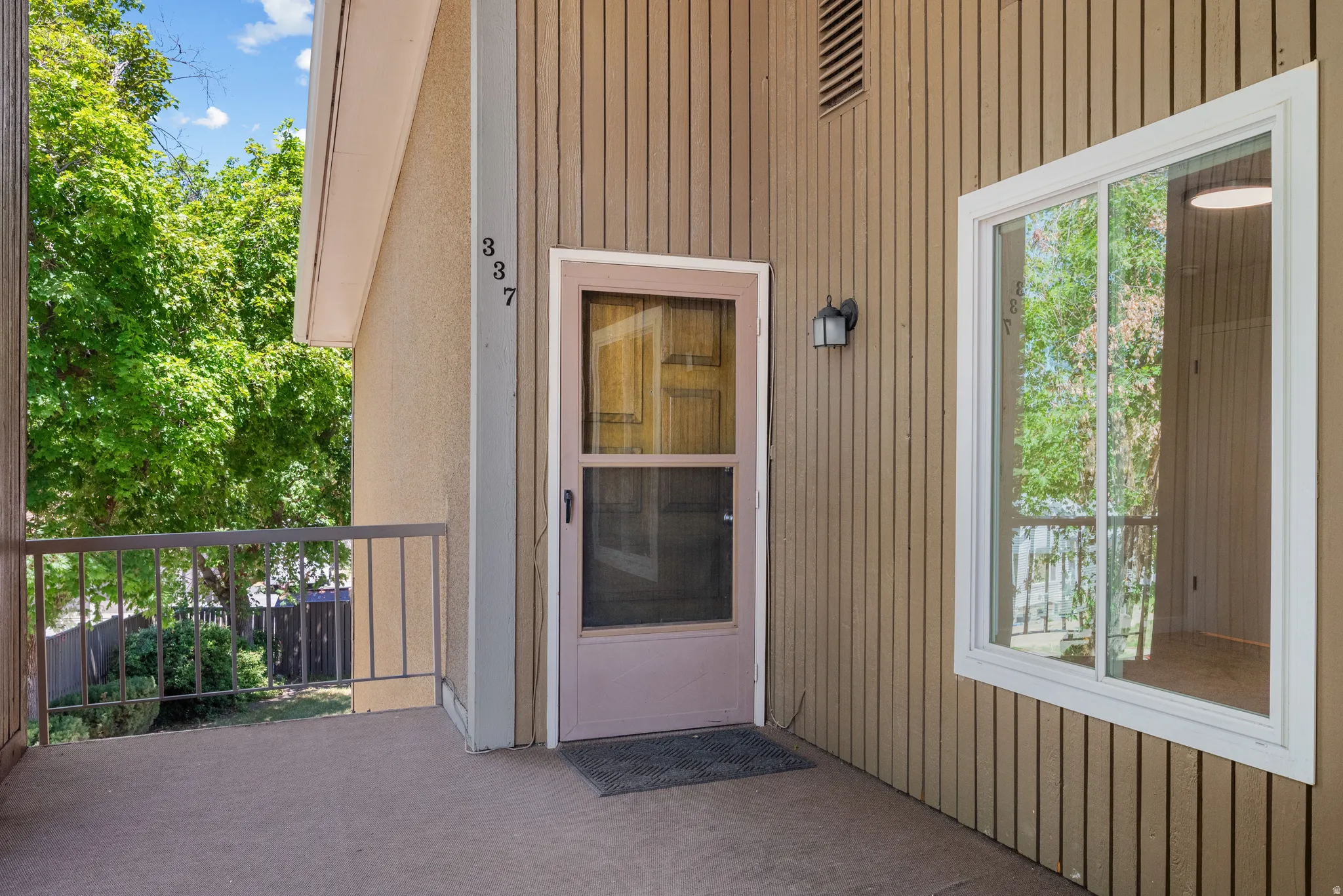 Front entry featuring a solid screen door, wall-mounted light fixture, and horizontal siding